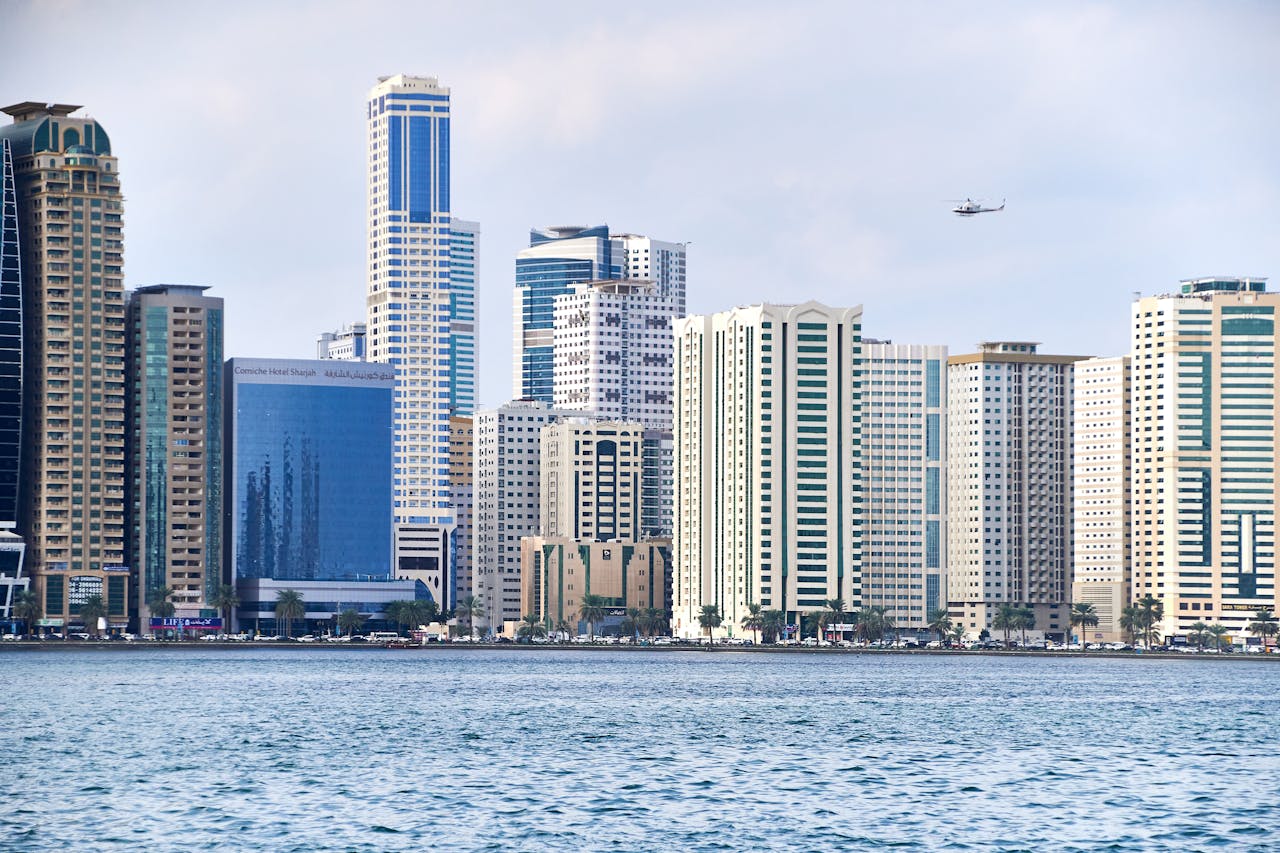 client-satisfaction-img Stunning view of Al Sharjah skyline with modern skyscrapers, sea, and helicopter passing by.